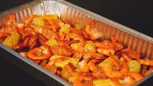 A tray of shrimp and corn on a table.