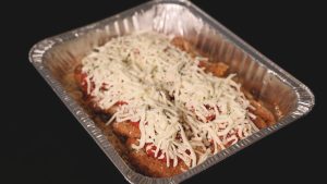 A tray filled with chicken and cheese in a silver container.
