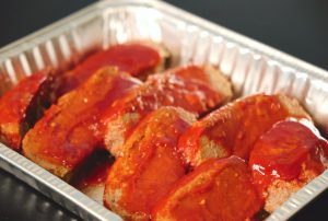 Meatloaf in a tray with sauce on it.