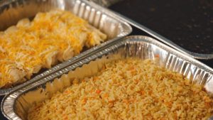 Two silver trays with rice and cheese in them.
