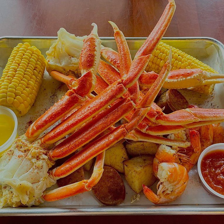 A tray of crab legs and corn on a table.