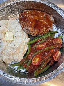 A plate with meat, mashed potatoes and green beans.